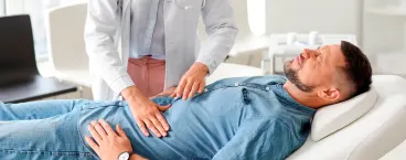 médica faz palpação em estômago de paciente