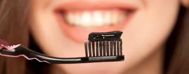 mulher a usar pasta dentífrica com carvão ativado