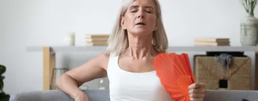 mulher de meia idade a abanar leque para atenuar o calor 