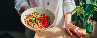 mulher a segurar taça de salada com leguminosas e legumes