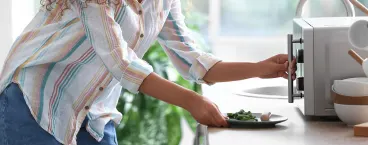 mulher a preparar-se para aquecer comida no microondas
