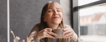 rapariga a sorrir enquanto bebe café