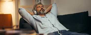 homem a ouvir música enquanto relaxa no sofá