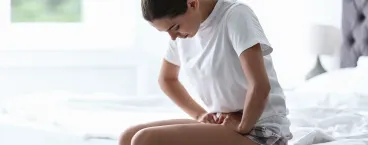 mulher sentada na cama com dores