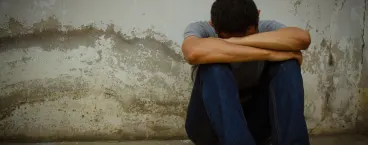 homem com a cabeça escondida entre as pernas