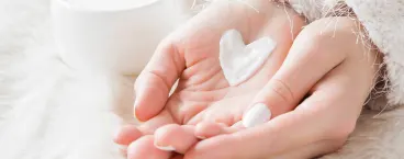 mulher com porção de creme na mão em forma de coração