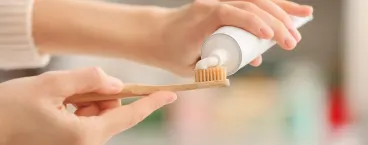 mulher a colocar pasta de dentes na escova