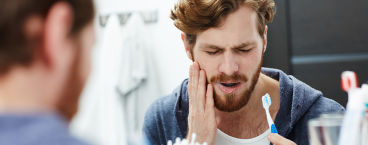 rapaz sente dor de dentes durante a escovagem