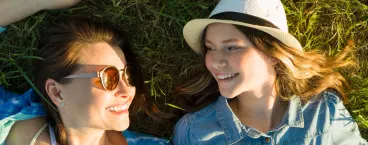 mãe e filha deitadas na relva felizes