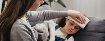 mãe aplica compressa na testa da filha