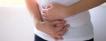 mulher com as mãos a pressionar a zona abdominal 