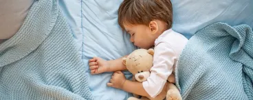 bebé a dormir abraçado a urso de peluche