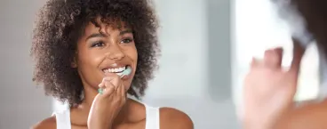 mulher a colocar pasta de dentes na escova elétrica