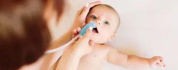 mãe a limpar o nariz do bebé com aspirador nasal