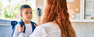 menina a segurar mochila pesada com mão