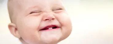 bebé a sorrir com dois dentes