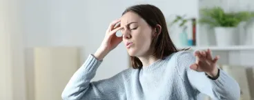 mulher com olhos fechados e mão na cabeça
