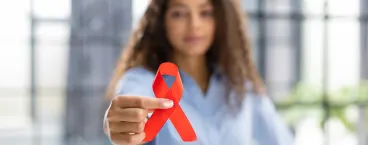 mulher a segurar laço vermelho símbolo da luta contra a Sida