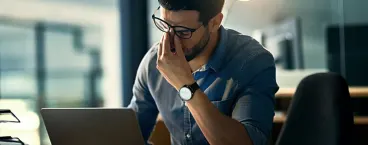 homem com ar preocupado e cansado em frente ao computador 