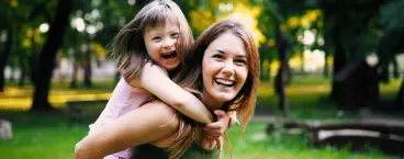 mãe com menino com Síndrome de down às cavalitas