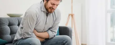 homem com dores a pressionar o abdómen