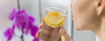 senhora a beber um copo de sumo de limão com uma rodela