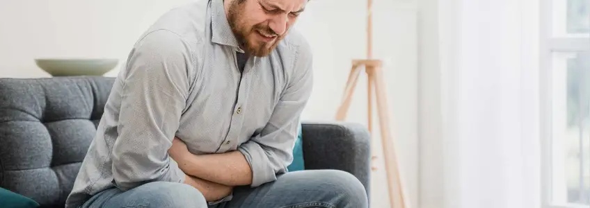 homem com dores a pressionar o abdómen