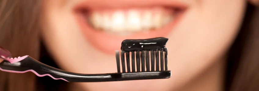 mulher a usar pasta dentífrica com carvão ativado