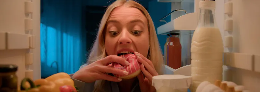 rapariga a comer um dónute à noite