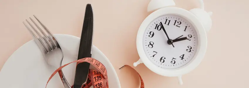 relógio, fita-métrica e prato dispostos numa mesa