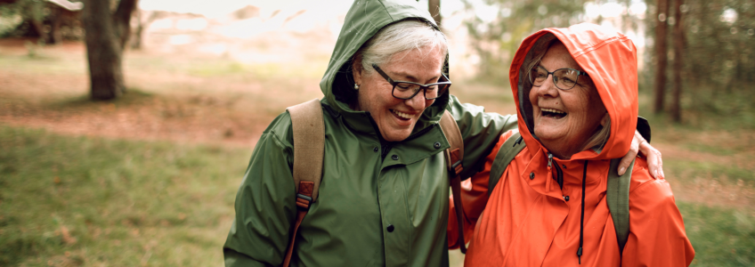 Séniores a rirem vestidas com uma parka no campo