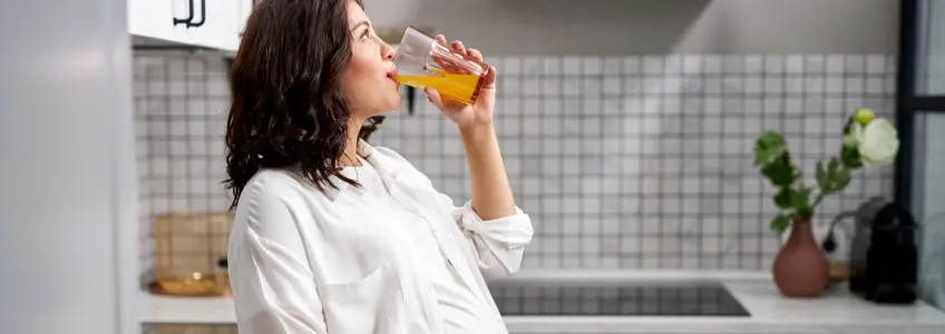 grávida a beber um sumo de laranja