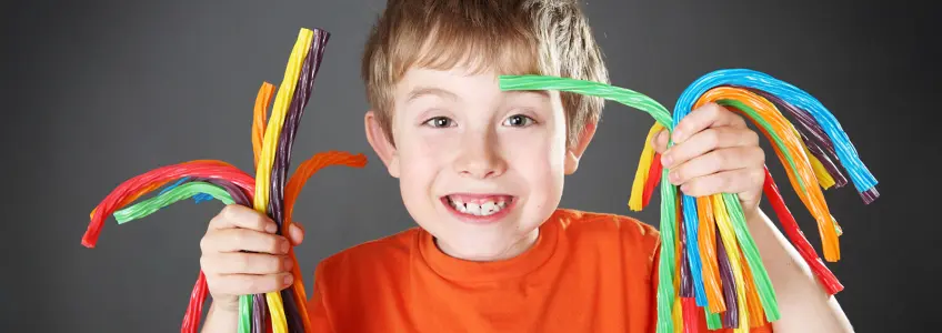 menino sorridente com muitas gomas na mão