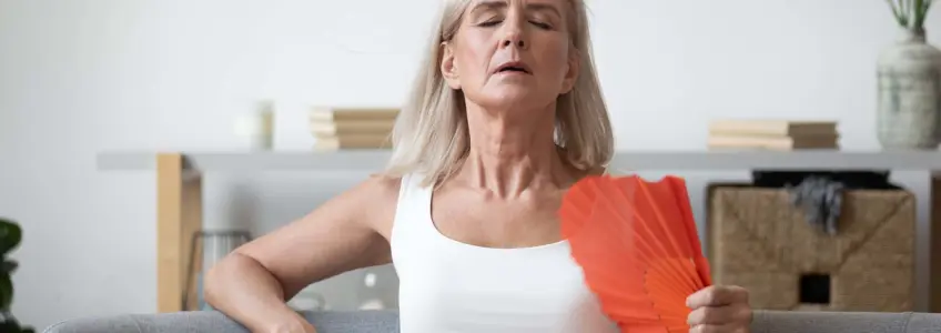 mulher de meia idade a abanar leque para atenuar o calor 