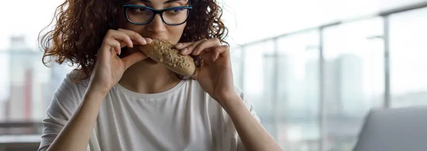 mulher em frente ao computador a comer pão