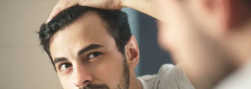 rapaz a mexer no cabelo enquanto olha ao espelho