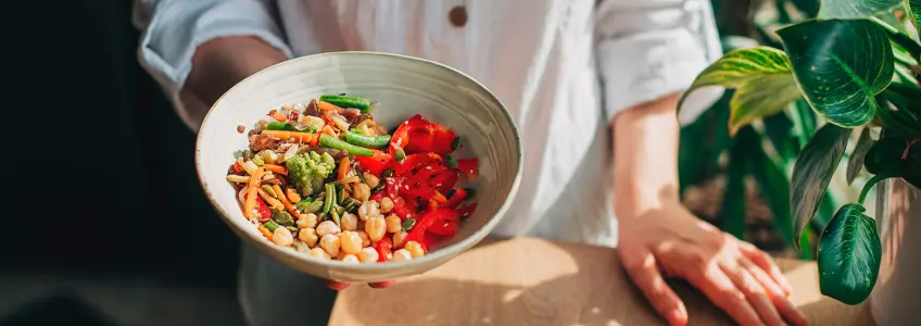 mulher a segurar taça de salada com leguminosas e legumes