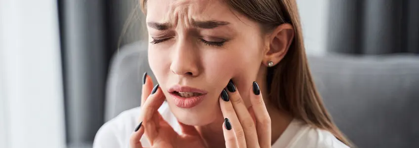 mulher com dor intensa causada pela alveolite dentária