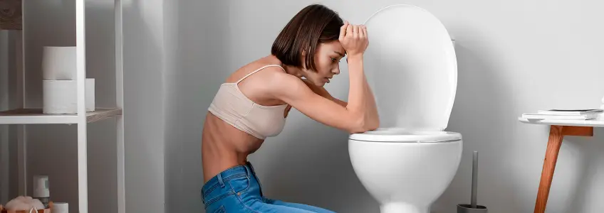 rapariga a tentar vomitar na casa de banho