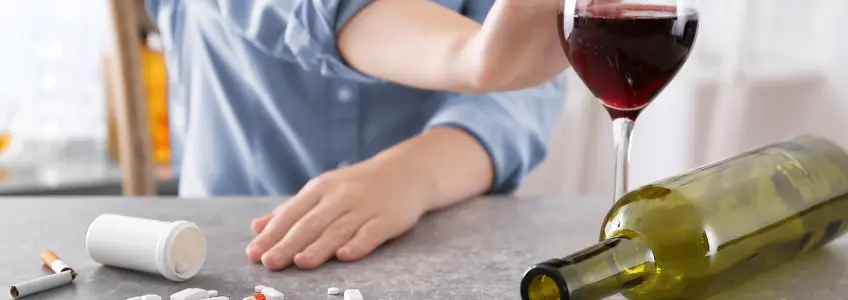 garrafa de vinho, comprimidos e cigarros e homem a recusar copo de vinho