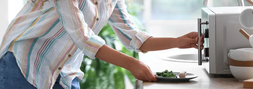 mulher a preparar-se para aquecer comida no microondas