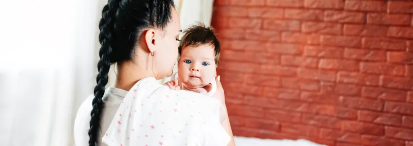 mãe segura no bebé na vertical após amamentar