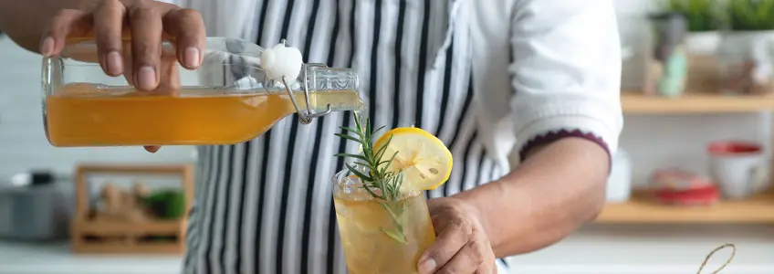 homem a servir um copo de kombucha