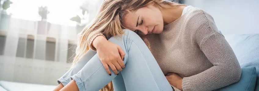 mulher com dor no abdómen causada pelo botulismo