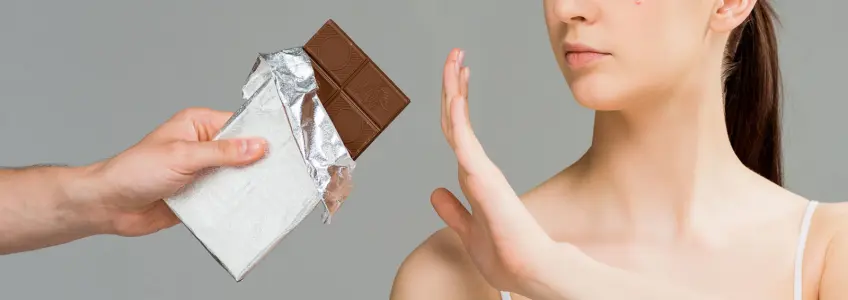 rapariga a comer chocolate com borbulhas na cara
