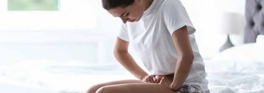 mulher sentada na cama com dores