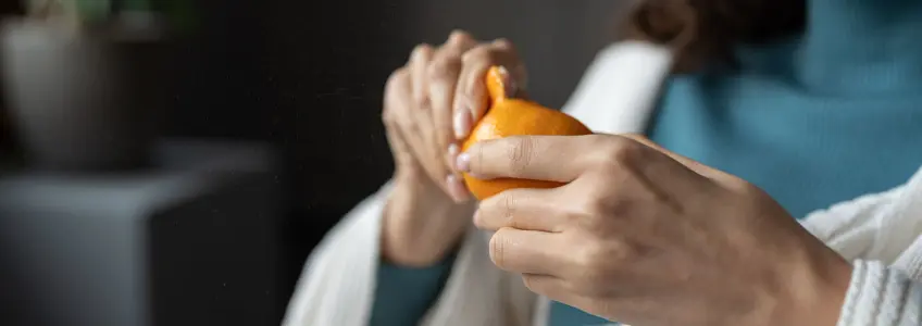 mulher a descascar laranja sentada no sofá