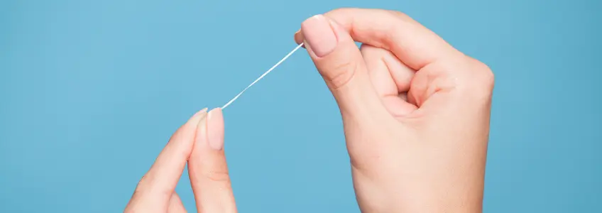 fio dentário numa mão de mulher
