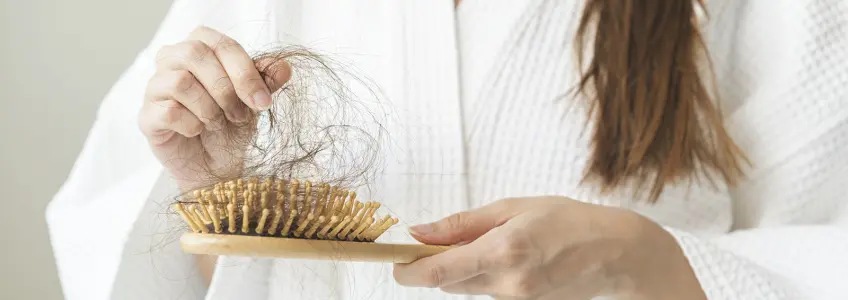 mulher retira fios de escova de cabelo