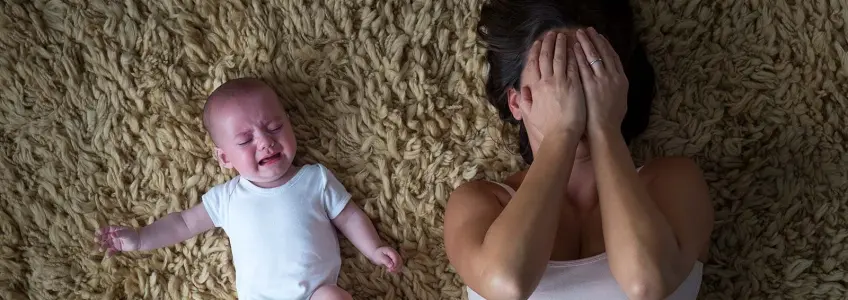 mãe com ar cansado segura bebé ao colo
